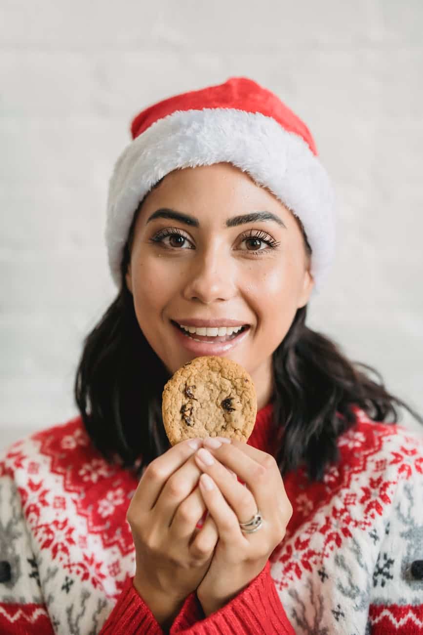 smiling female with chocolate cookie looking at camera against brick wall